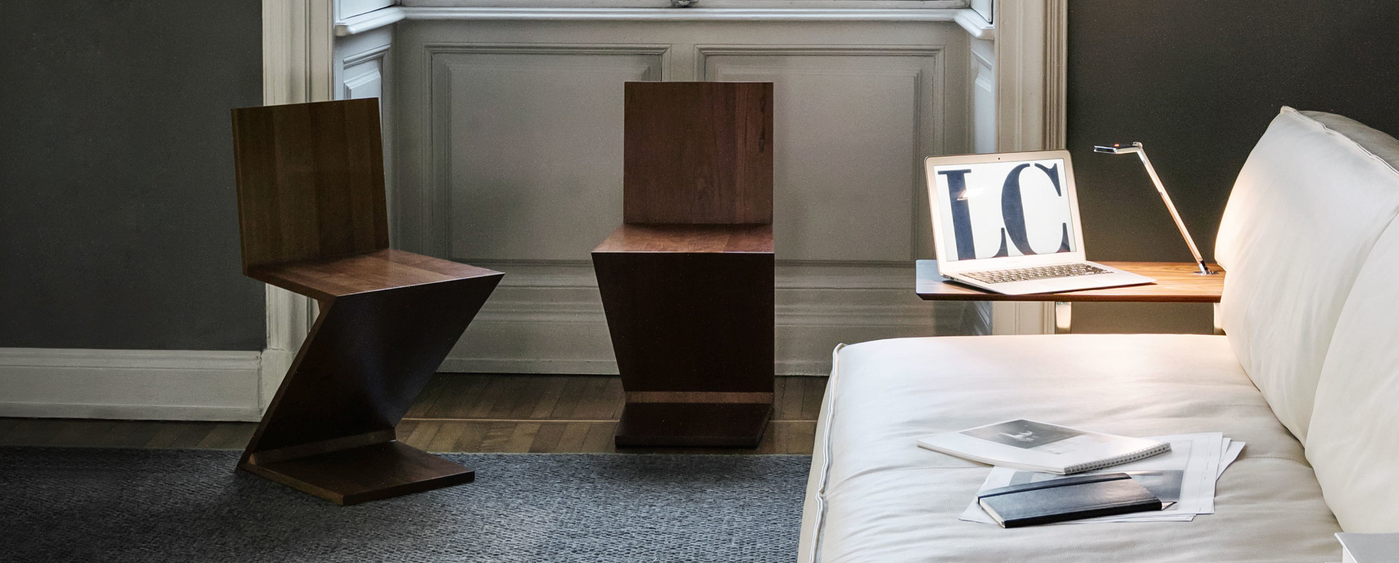 Zwei Cassina Zig Zag Stühle aus Holz im modernen Wohnzimmer mit Sofa und Laptop.