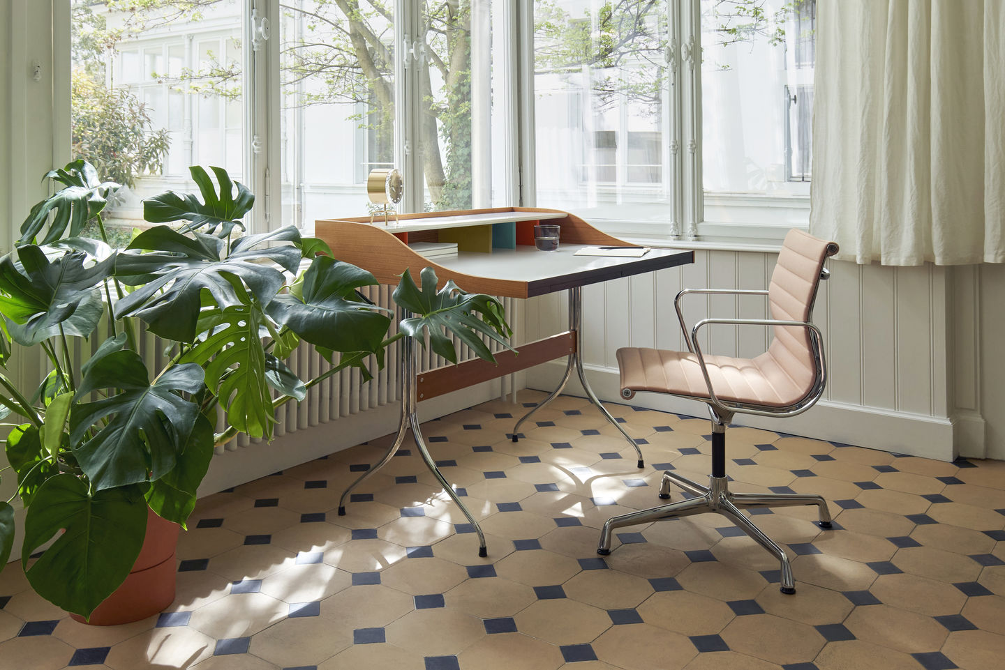 Vitra Aluminium Chair EA 104 in Rosé vor Schreibtisch mit Zimmerpflanze in hellem Raum.