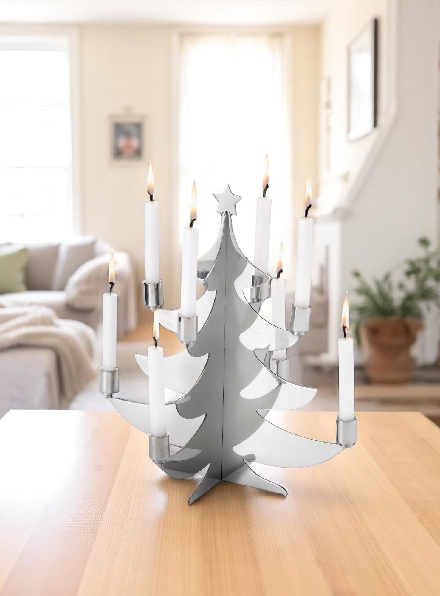 Philippi Grenoble Weihnachtsbaum für Kerzen aus poliertem Edelstahl mit brennenden, weißen Kerzen auf einem Holztisch.