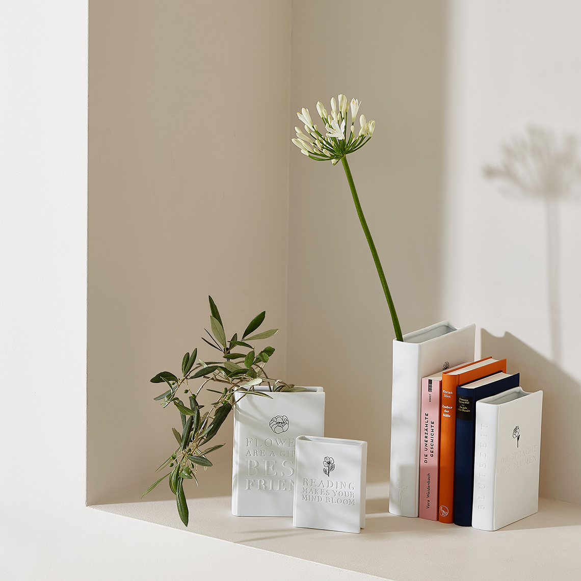Weiße "Geschichten schreiben" Vasen von Räder mit Blumen und Büchern als Dekoration.