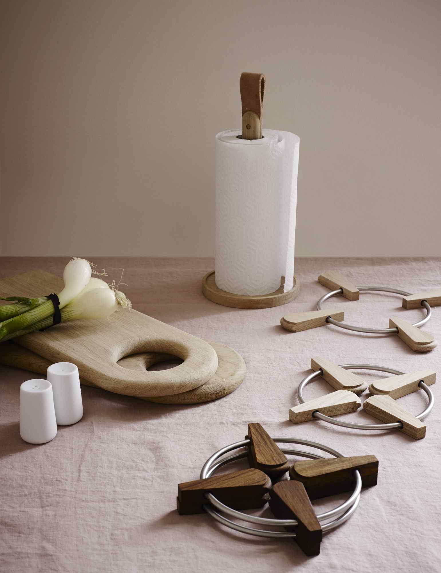 Norr Küchenrollenhalter aus Holz mit Ledergriff, neben Schneidebrett und Topfuntersetzern.