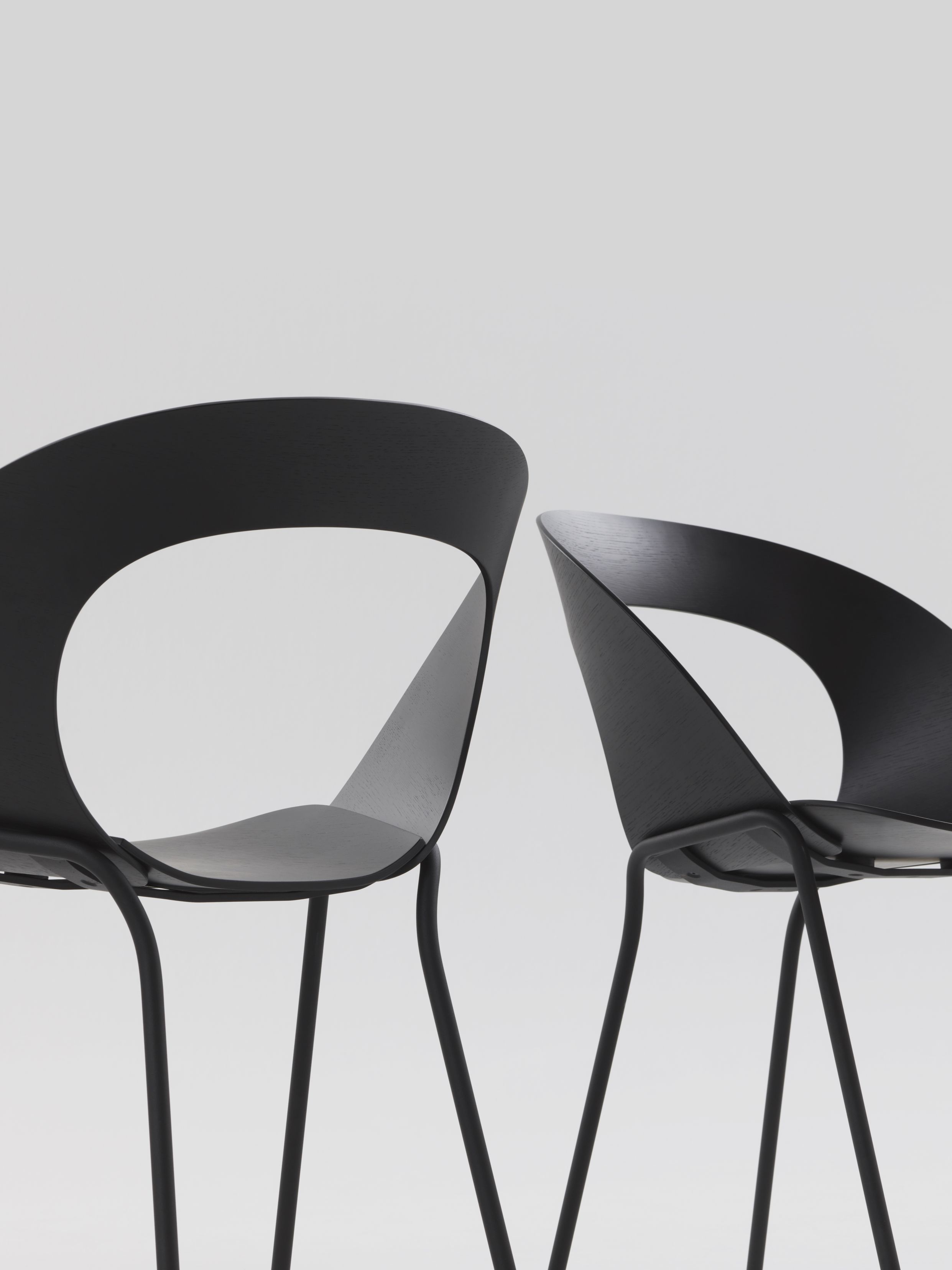 Zwei schwarze Brunner Mudra Stühle mit minimalistischem Design und Stahlbeinen vor neutralem Hintergrund.