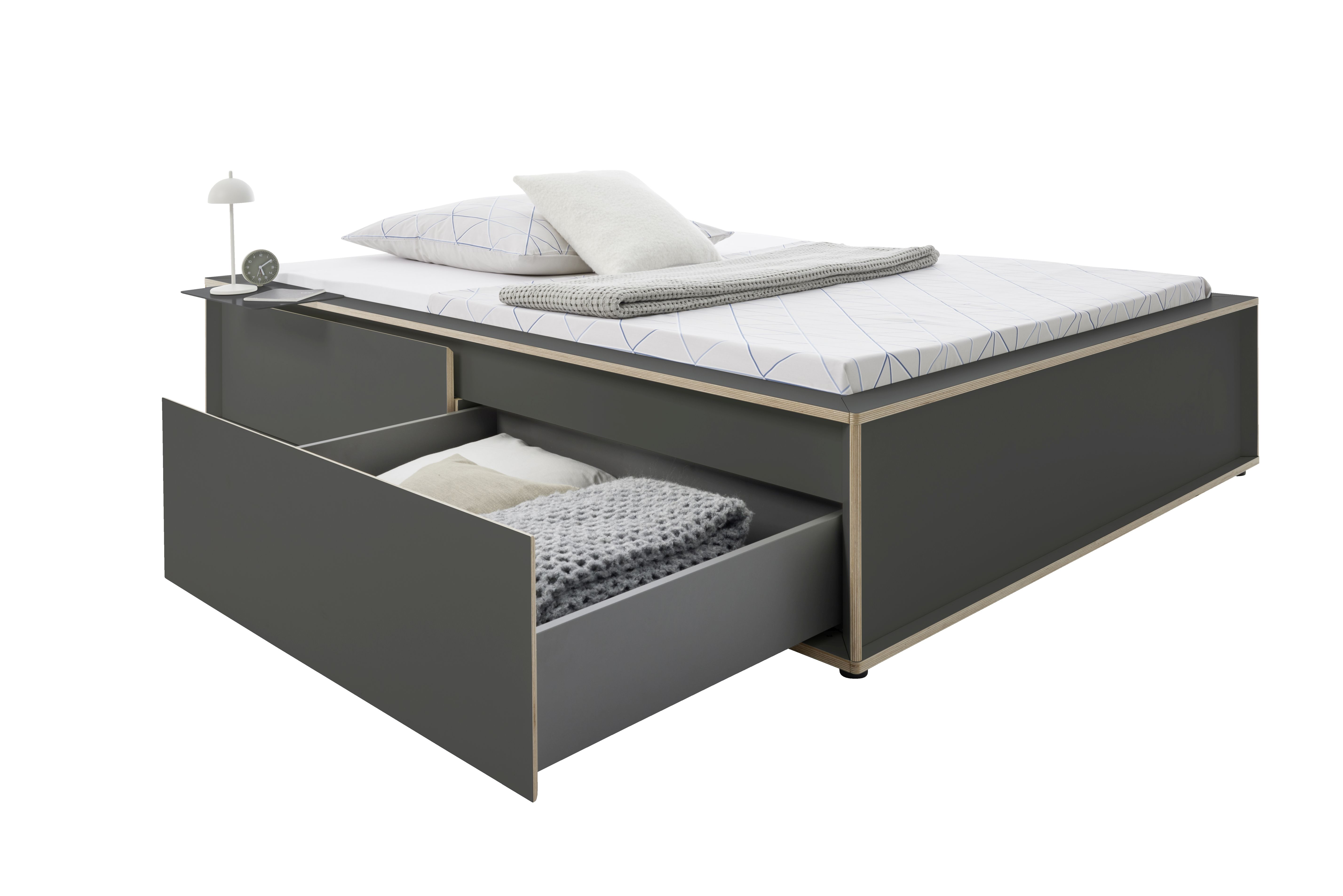 Spaze Bett von Müller Möbelwerkstätten in Grau mit Schublade, Nachttisch, Lampe, Kissen und Decke.