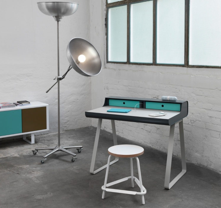 Modernes Arbeitszimmer mit Schreibtisch, Hocker, Stehlampe und Kommode in Weiß, Grau und Türkis.
