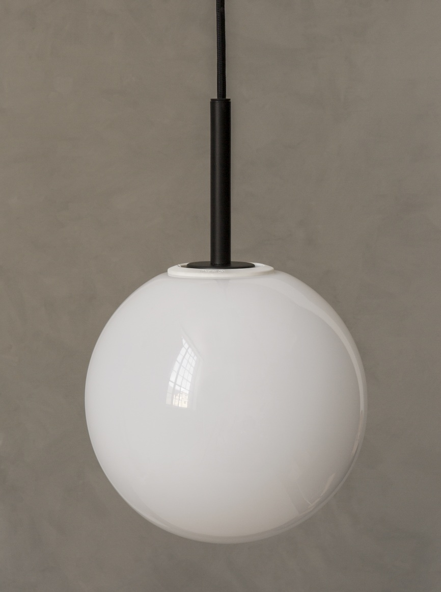 Nahaufnahme der Audo TR Bulb Pendelleuchte mit weißem Opalglas-Diffusor und schwarzer Aufhängung vor grauer Wand.