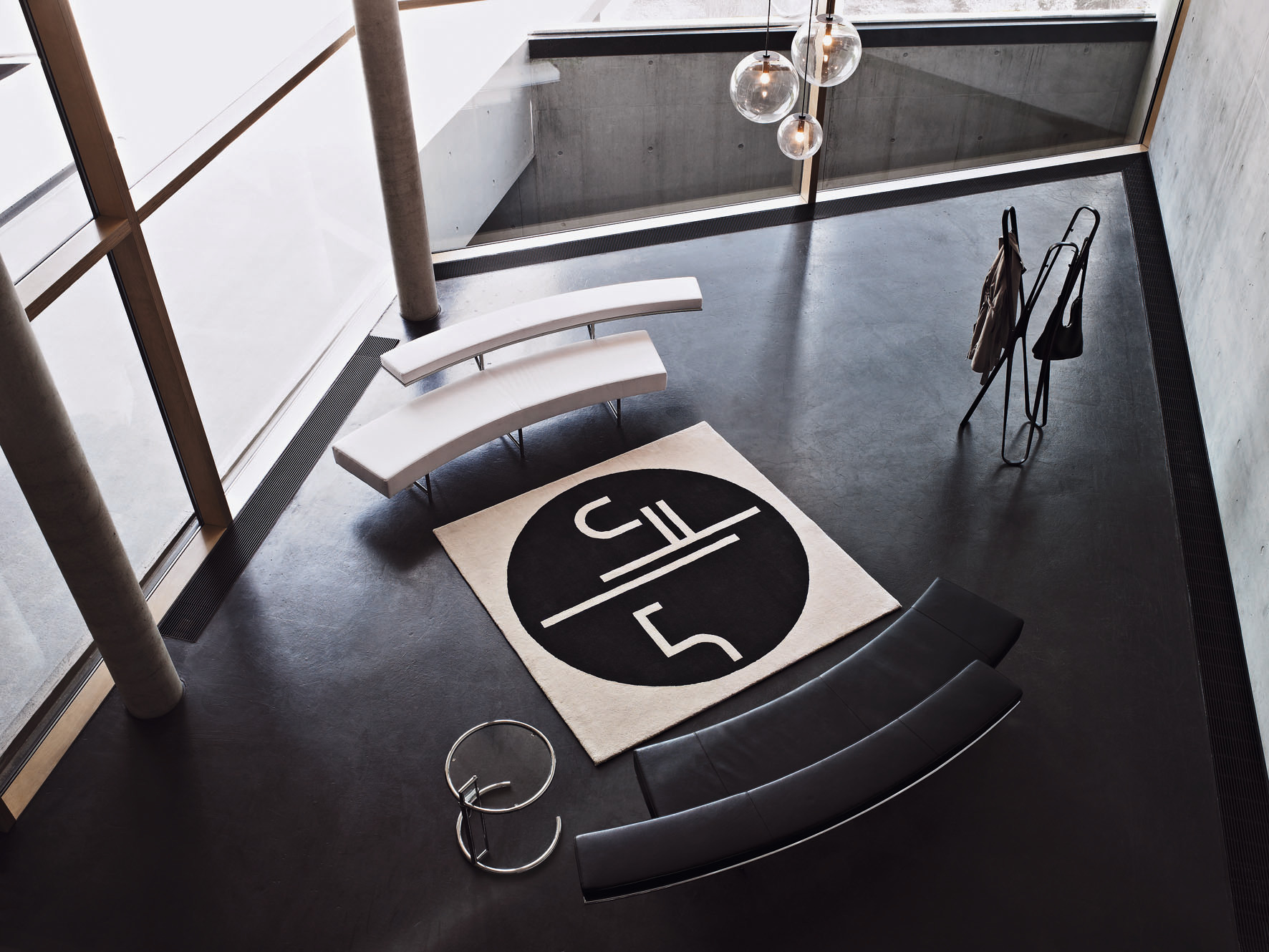 Luftaufnahme eines modern eingerichteten Raumes mit ClassiCon Adjustable Table E1027 Beistelltisch, Teppich und Sitzmöbeln.