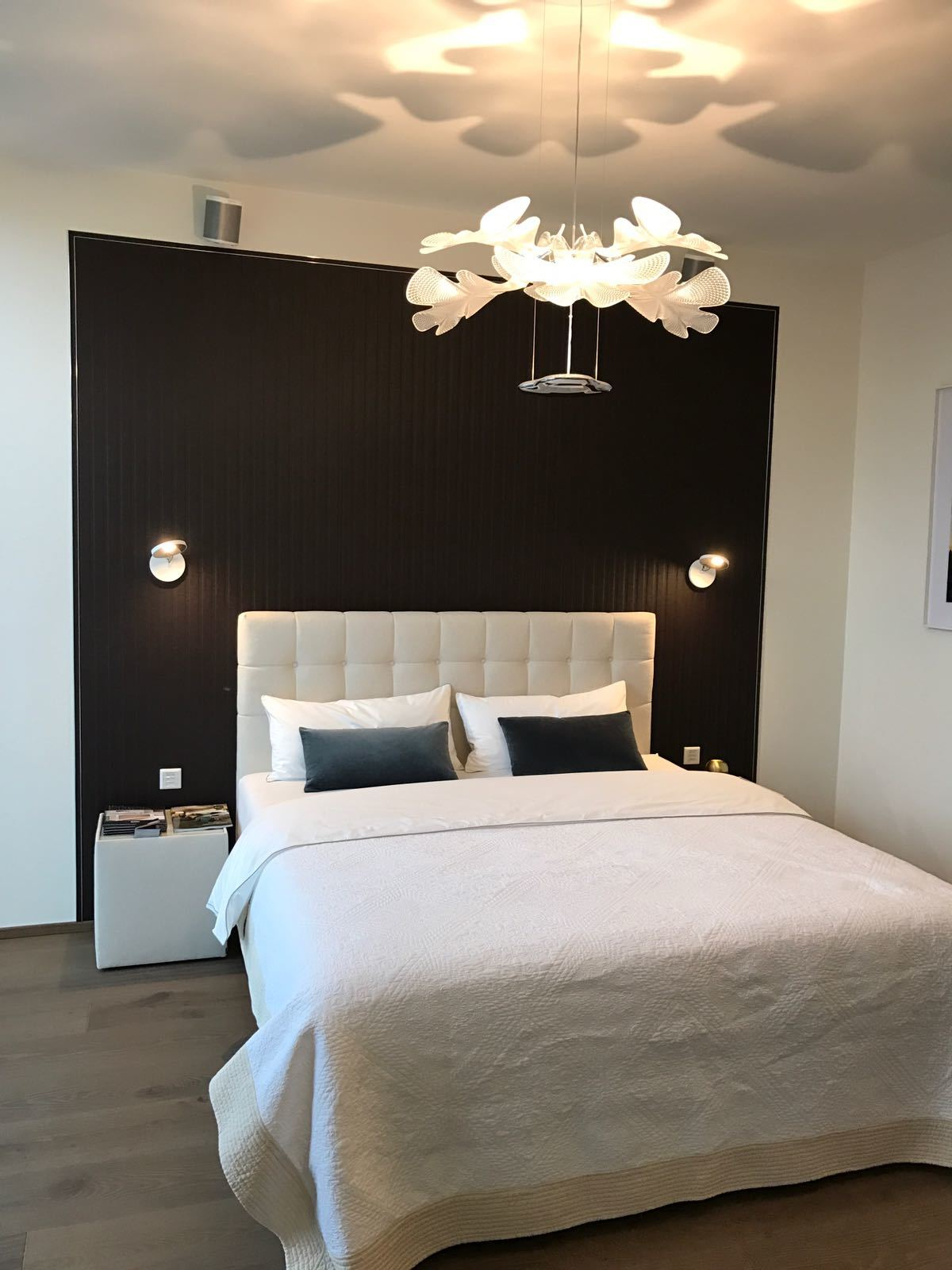 Moderne Chlorophilia Pendelleuchte von Artemide über einem Bett im Schlafzimmer mit chromfarbener Struktur und transparentem Diffusor.