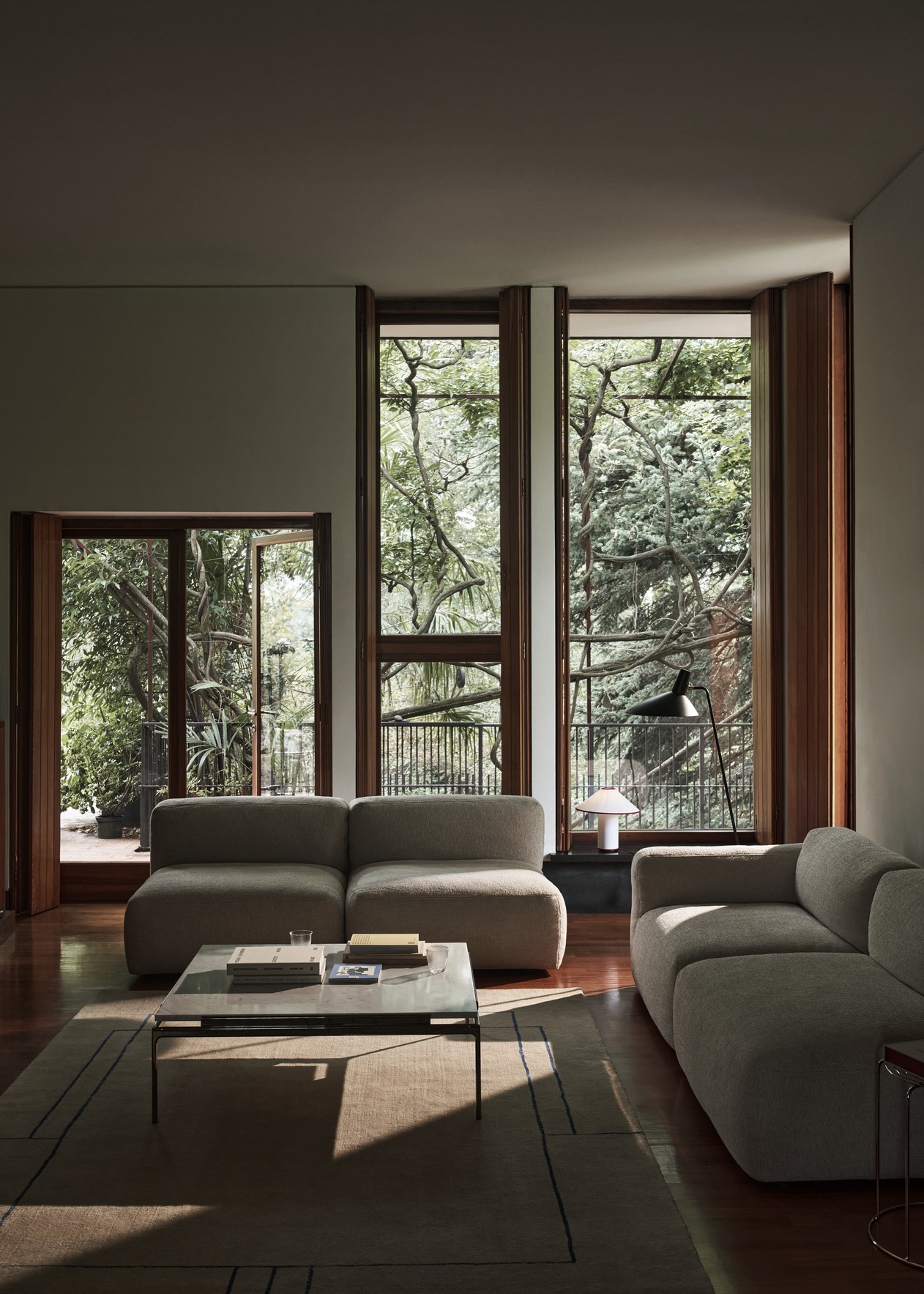 Wohnzimmer mit modularem Sofa und AndTradition Sett Couchtisch mit Glasplatte auf Teppich.