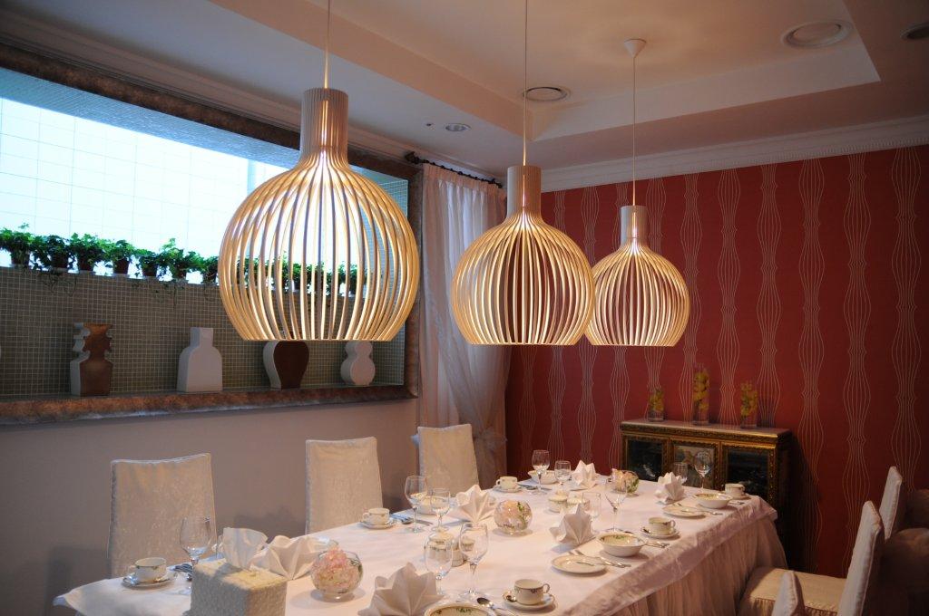 Drei Octo Pendelleuchten von Secto Design hängen über einem gedeckten Tisch in einem eleganten Esszimmer.