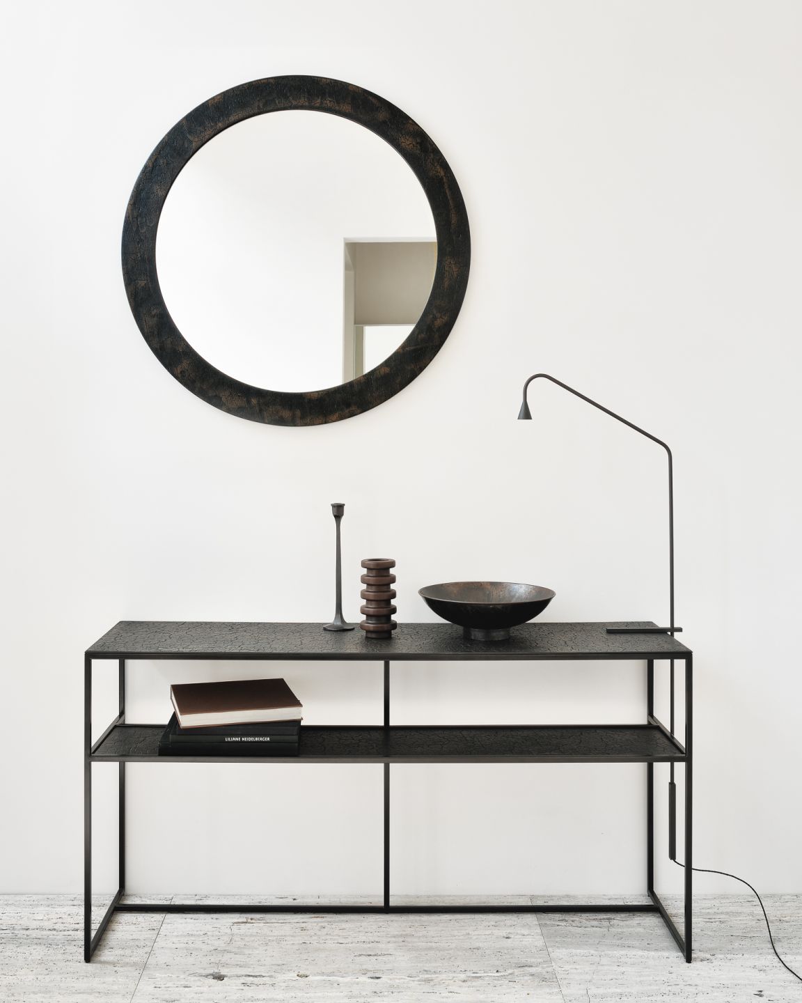 Pentagon Konsole Lava von Ethnicraft mit rundem Spiegel, Lampe und Deko-Elementen vor einer weißen Wand.