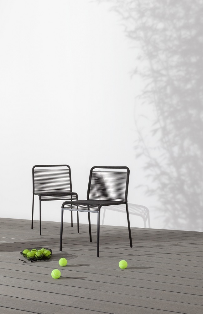 Zwei schwarze ARIA S42 Outdoor Stühle auf einer Terrasse mit Tennisbällen im Vordergrund.