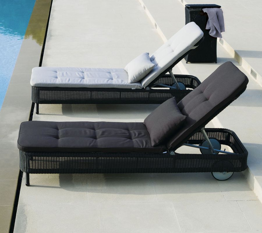 Zwei schwarze Cane-Line Sonnenliegen mit Outdoor Kissen, ideal für Pool und Garten.