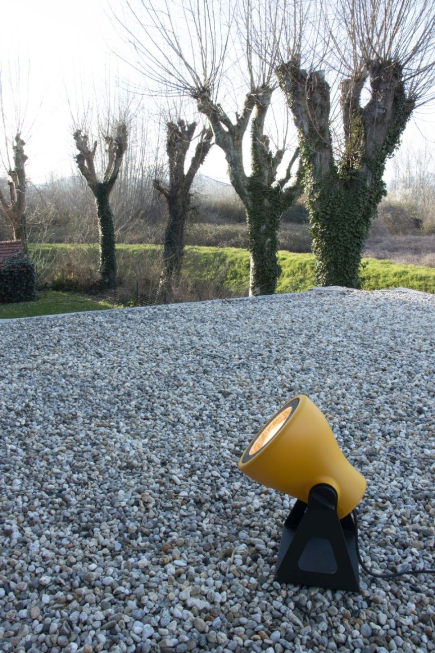 Gelbe Mini Frog Outdoor Leuchte von Martinelli Luce auf Kiesboden, Bäume im Hintergrund. Gartenbeleuchtung.