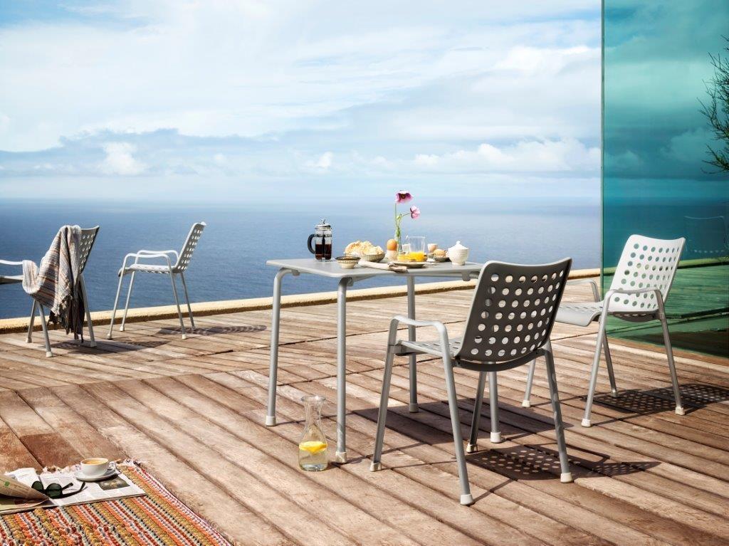 Helle Landi Stühle von Vitra auf einer Holzterrasse mit Meerblick, ideal für den Außenbereich.