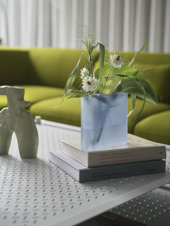 Hellblaue Vase mit Blumen auf Büchern, dekoratives Wohnaccessoire für stilvolles Interieur.