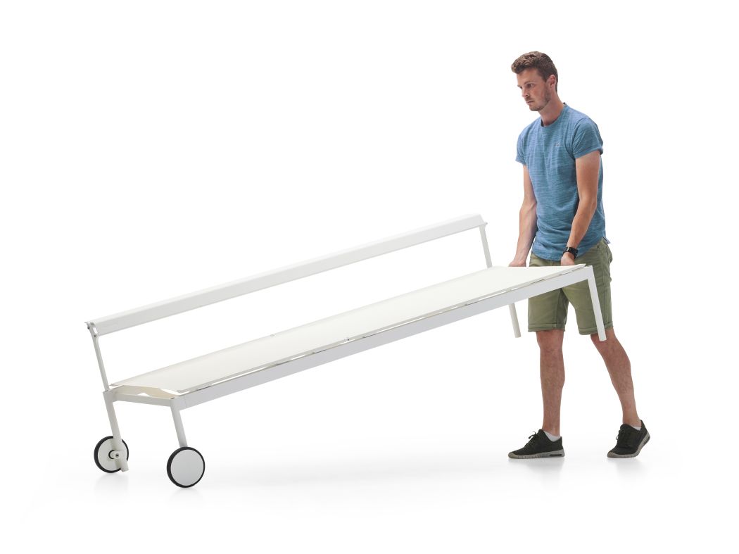 Mann transportiert weiße Sol + Luna Sonnenliege von Extremis mit Rollen für den Garten.
