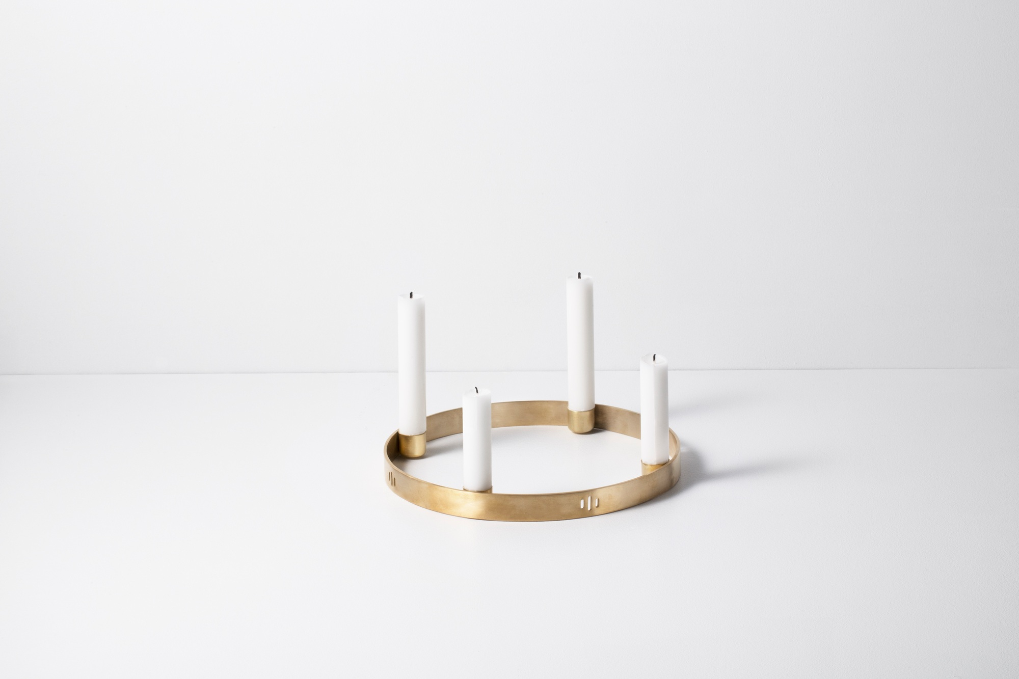 Großer, runder Kerzenhalter aus Messing von Ferm Living mit vier weißen Kerzen.