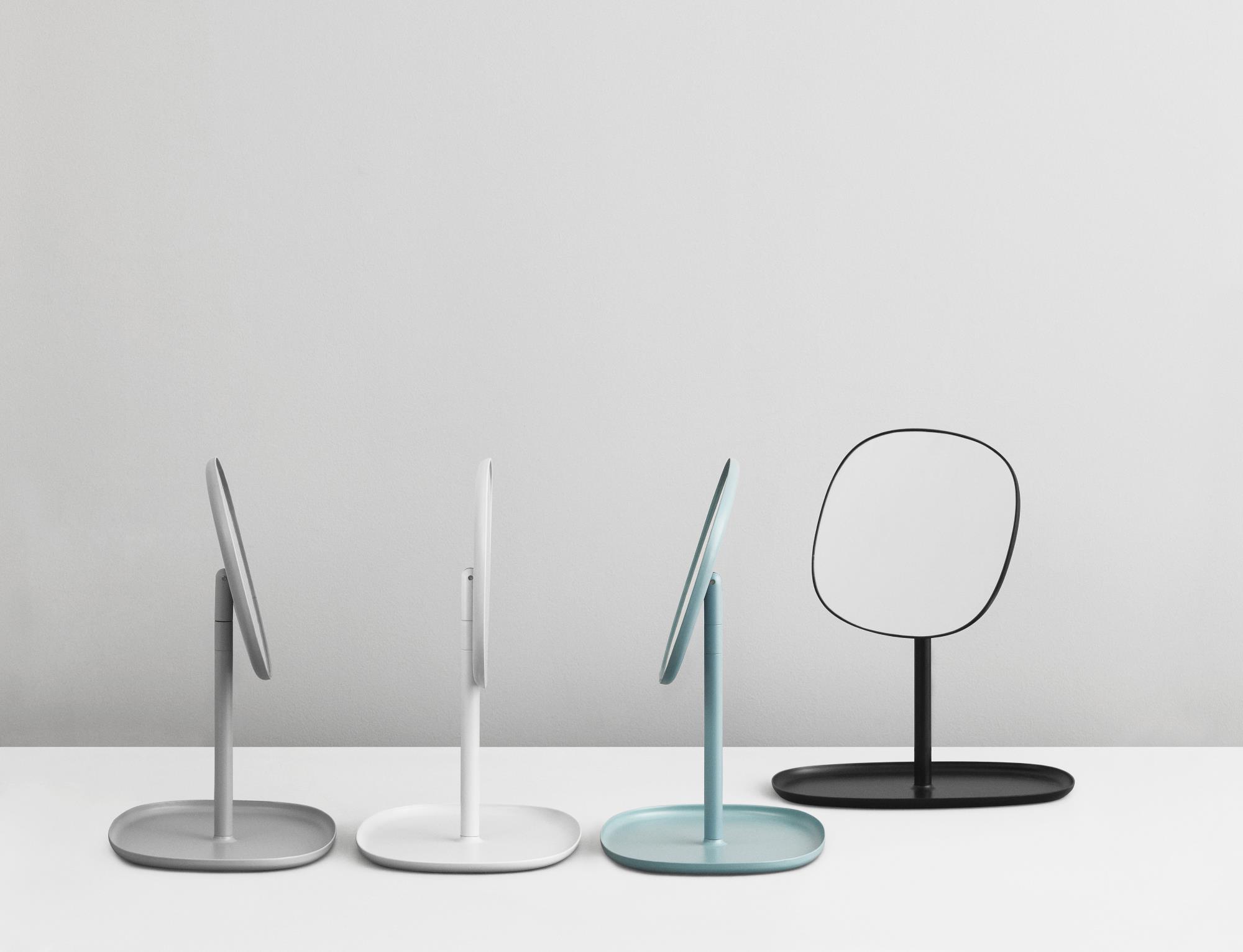 Verschiedenfarbige Normann Copenhagen Flip Spiegel: Grau, Weiß, Blau und Schwarz auf einem weißen Tisch.