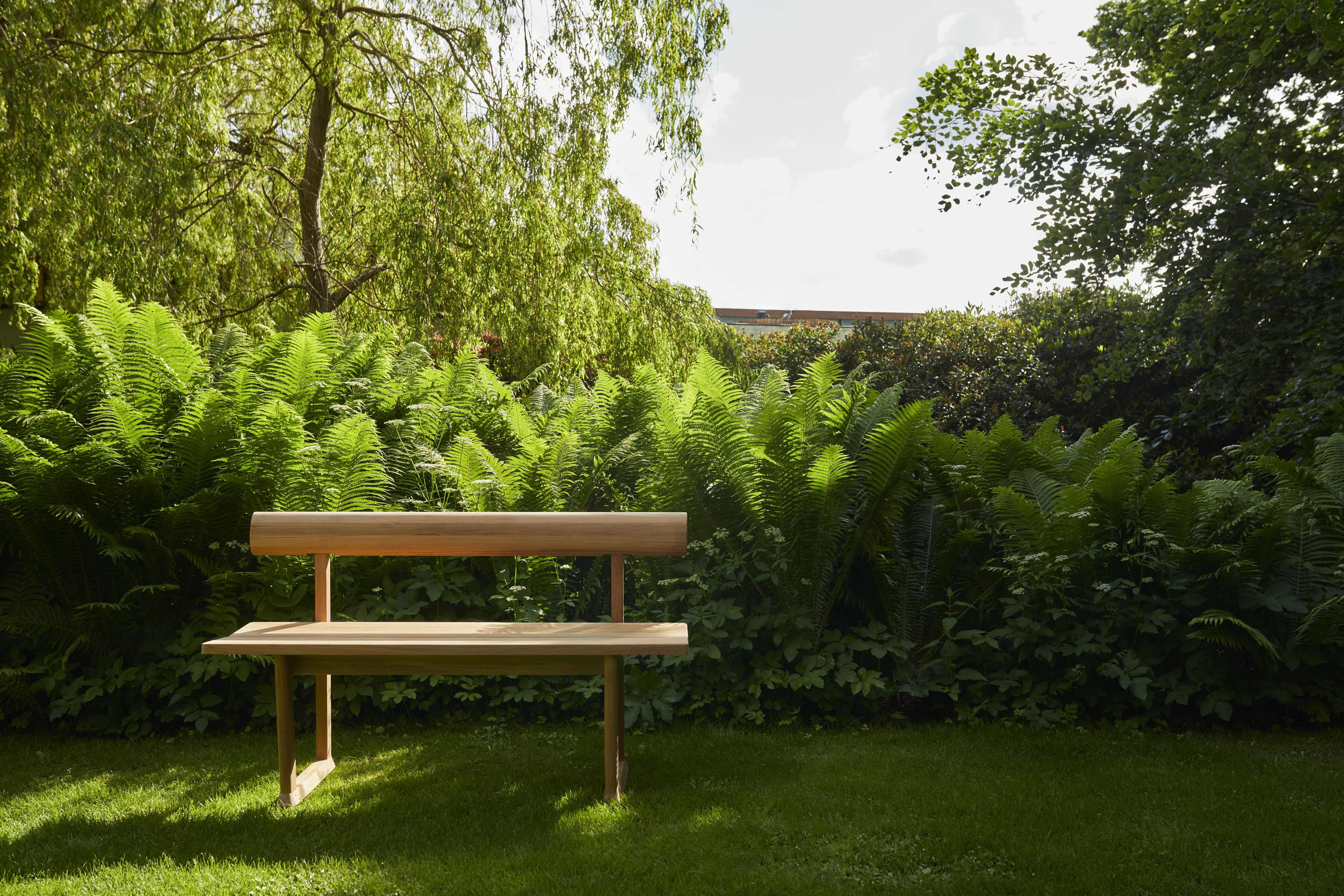Banco Bank aus Teakholz von Skagerak by Fritz Hansen im Garten, umgeben von Grünpflanzen.