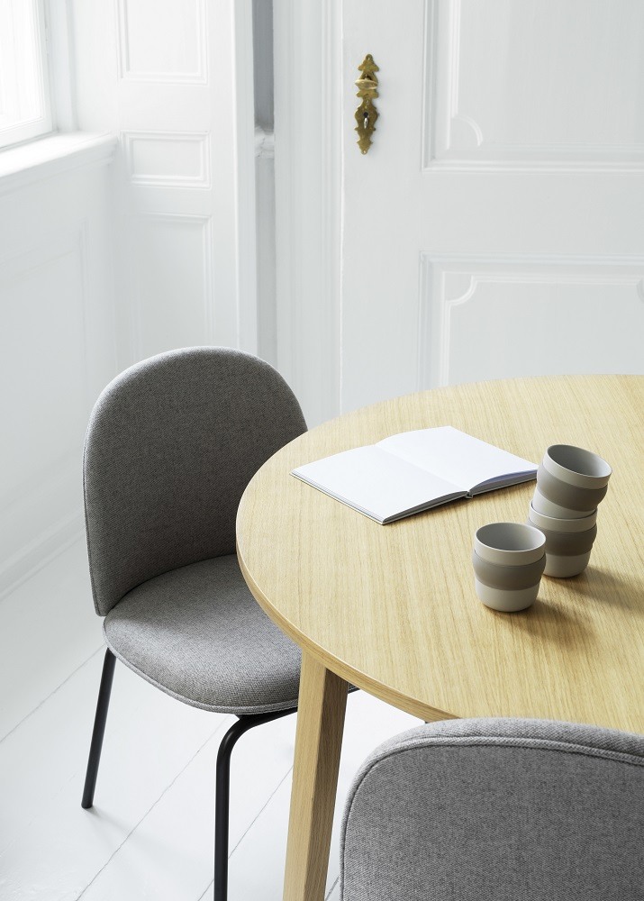 Ace Chair Stuhl von Normann Copenhagen, gepolstert mit grauem Stoff und schwarzen Beinen am Holztisch.