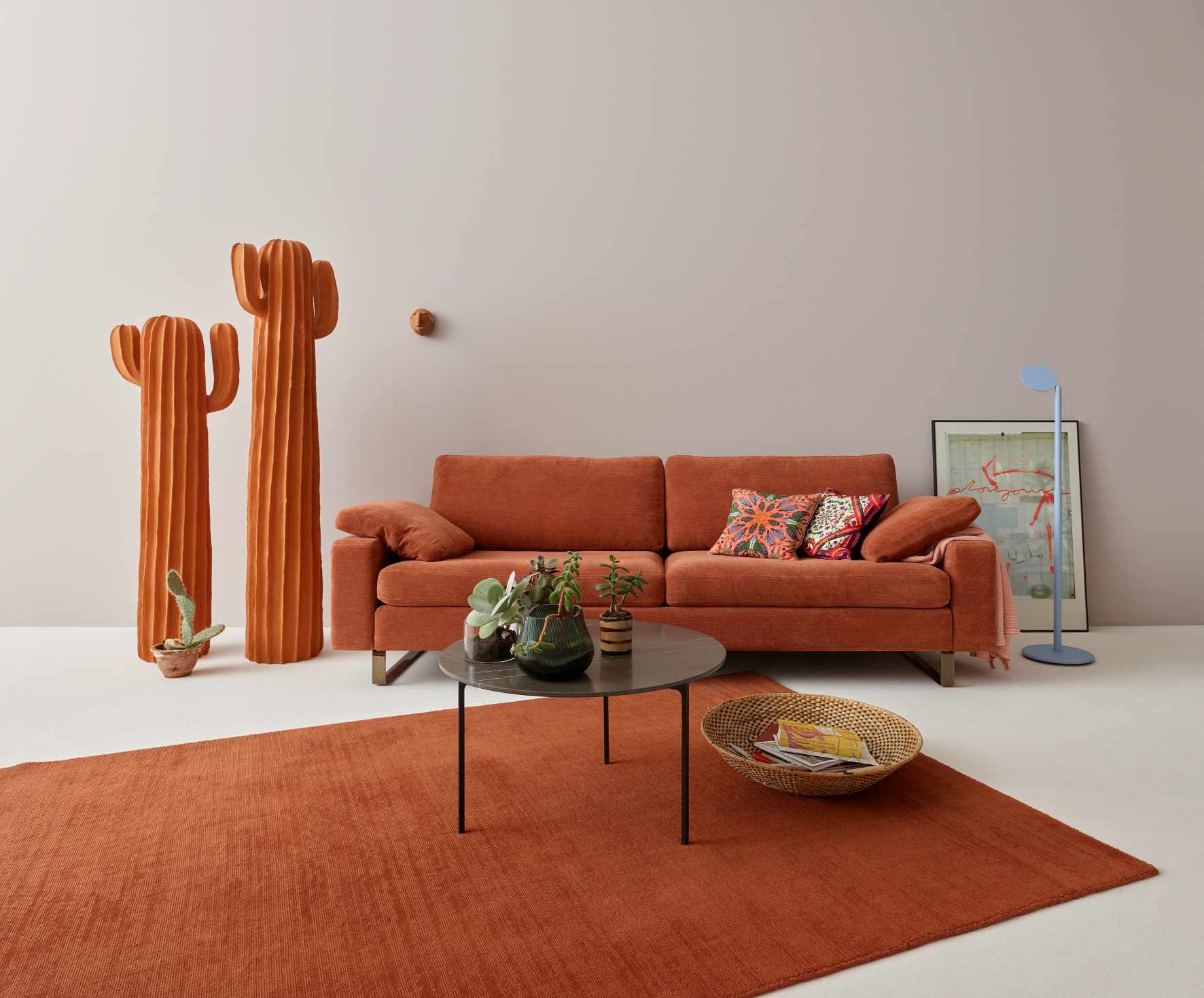 Orangefarbenes Conseta Sofa von Cor mit Couchtisch, Teppich und Deko-Elementen im Wohnzimmer.