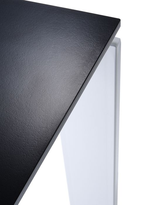 Detailaufnahme einer schwarzen Tischplatte mit weißem Tischbein, modernes Möbeldesign für Esszimmer oder Büro.