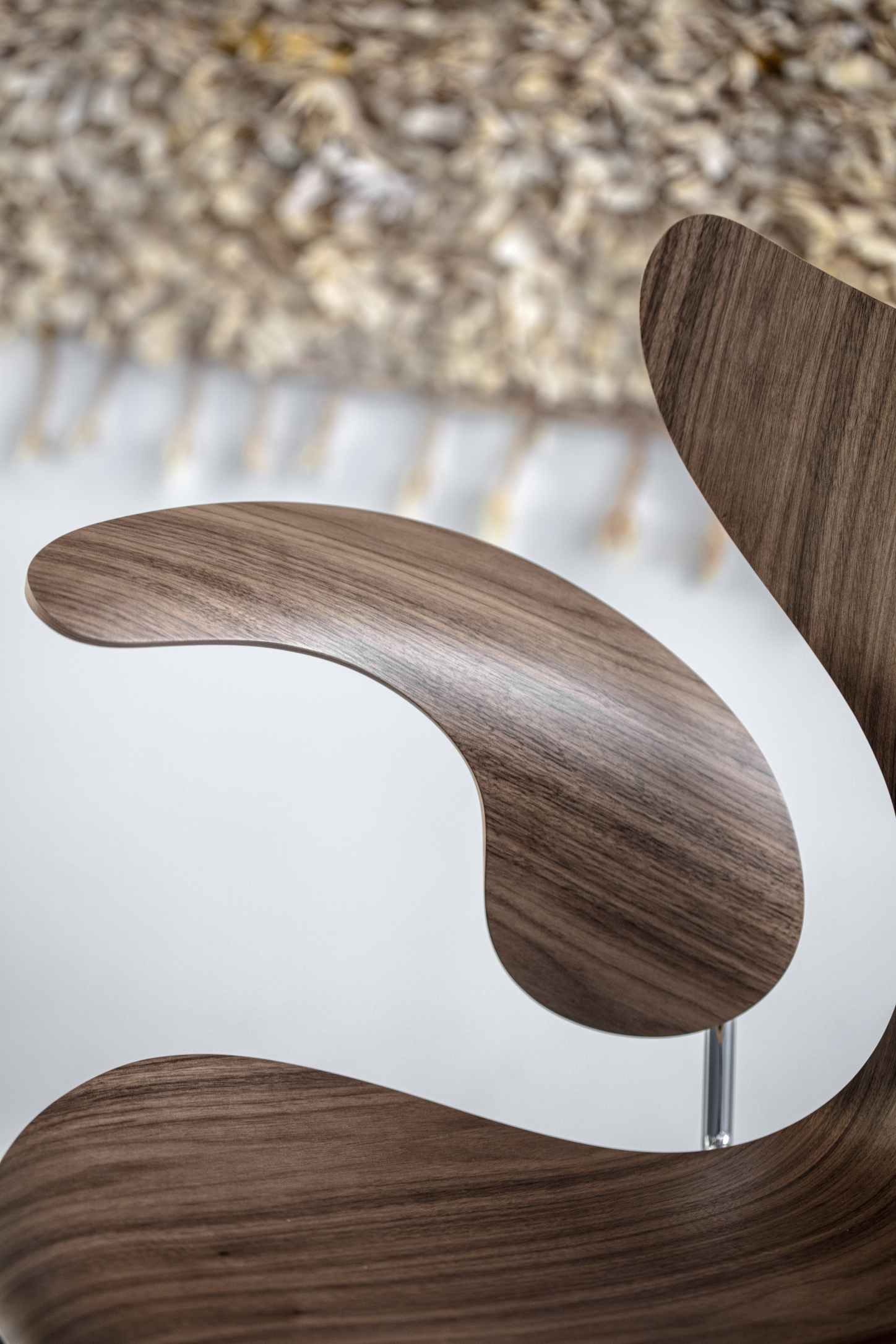 Detailaufnahme des Fritz Hansen Lily Armlehnstuhls 3208 mit Walnussholzfurnier und filigranem Chromfuß.