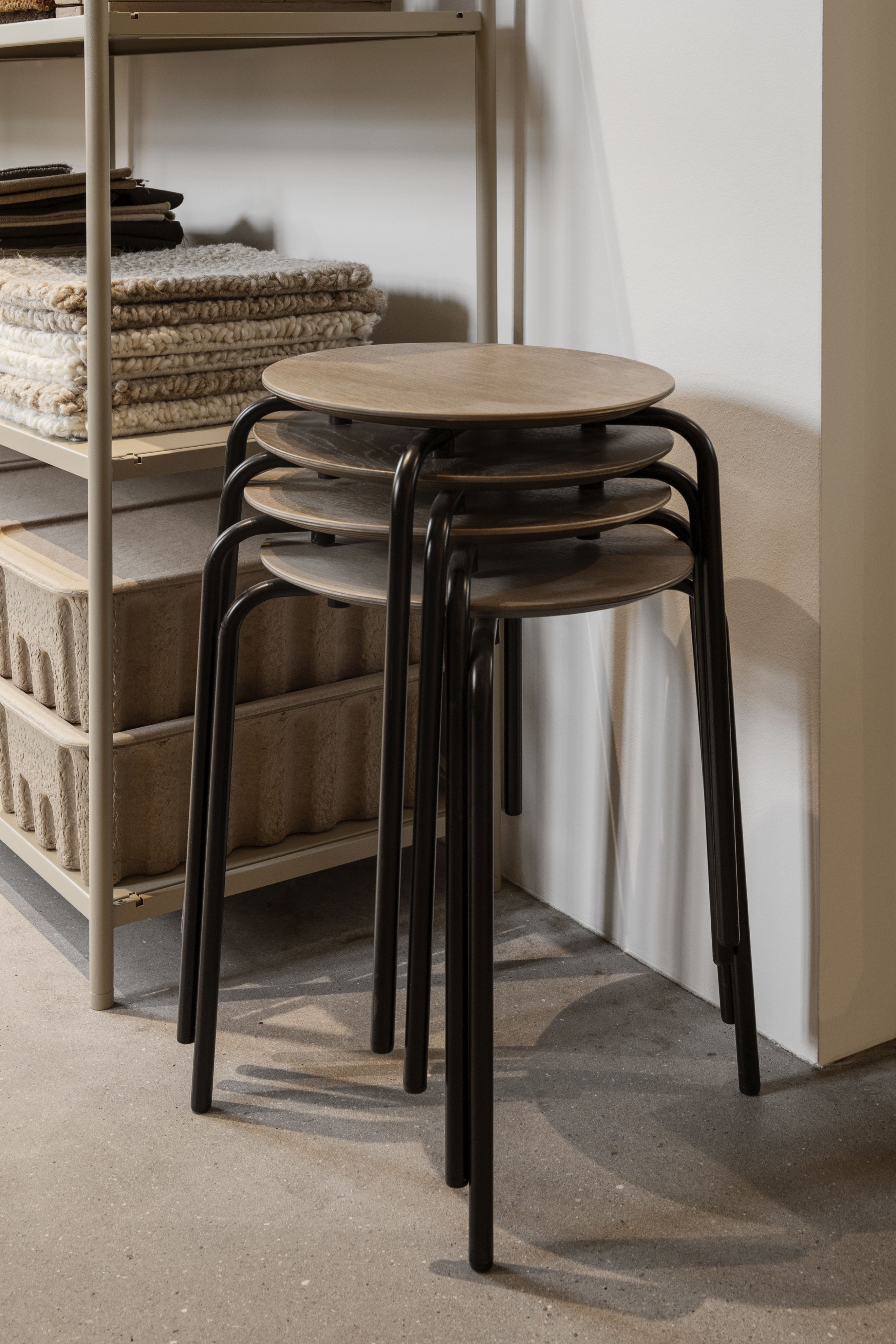 Stapelbare Herman Hocker von Ferm Living mit schwarzem Gestell und Holzplatte. Moderner Hocker für Wohnraum.