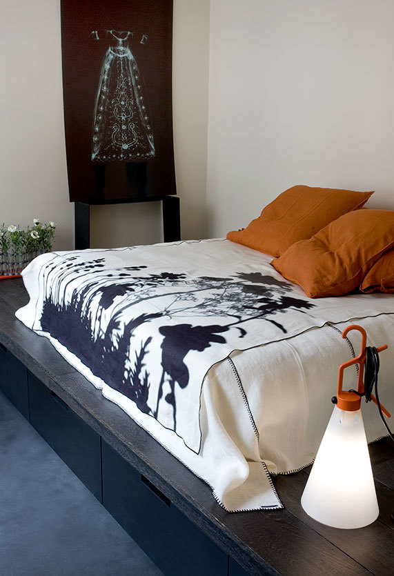 May Day Leuchte von Flos neben Bett mit Decke und Kissen, modernes Wohnambiente.
