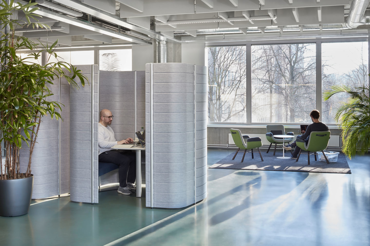Helles Büro mit East River Chair Sesseln von Vitra, Arbeitskabinen und großen Fenstern für moderne Büroeinrichtung.