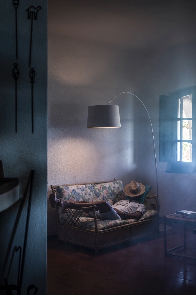 Twiggy Wood LED Stehleuchte von Foscarini über Sofa mit schlafendem Mann im Wohnzimmer.