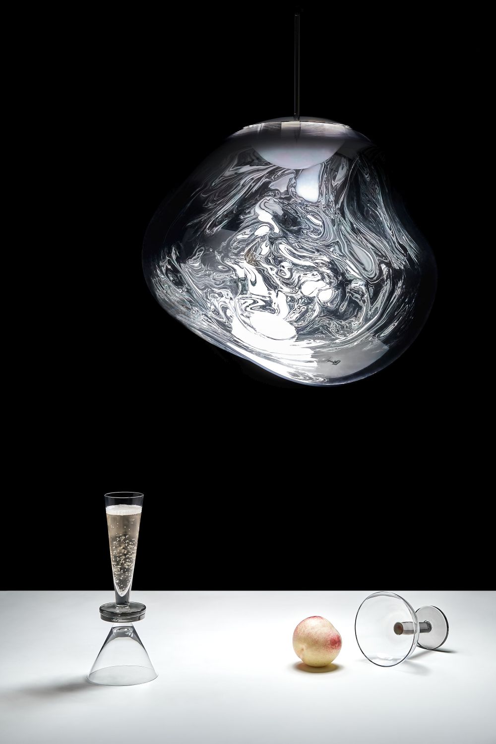 Silberne Melt LED Hängeleuchte von Tom Dixon über einem Tisch mit Pfirsich und Sektglas.