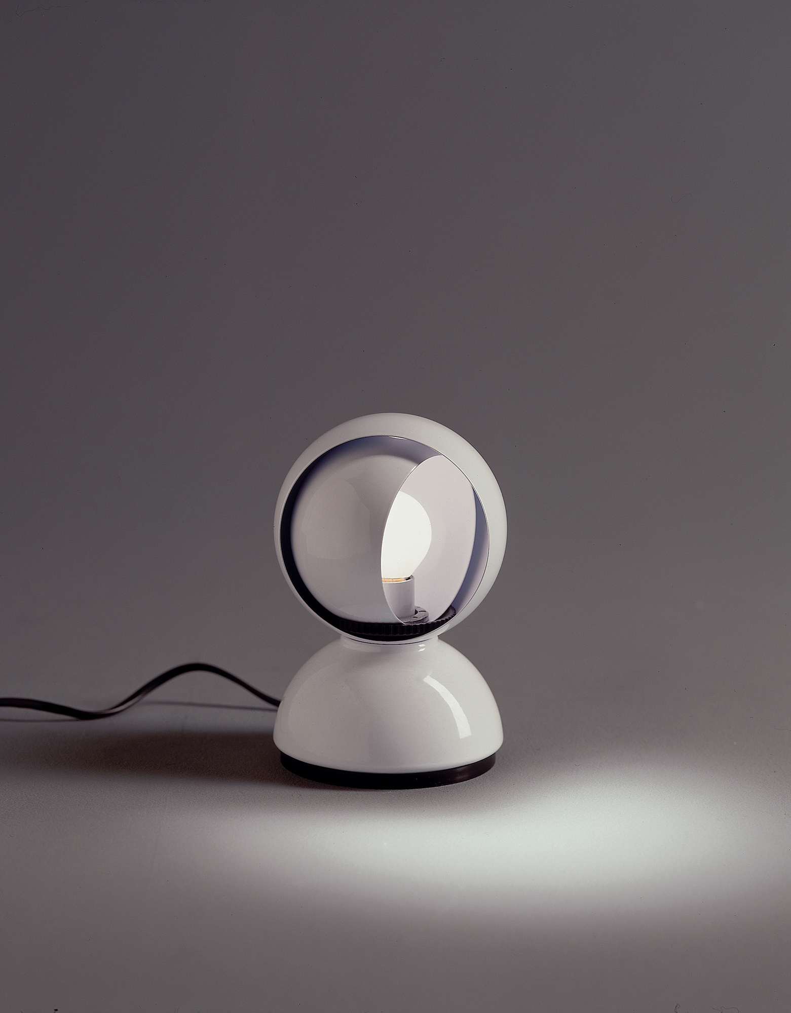 Weiße Artemide Eclisse Tischleuchte mit verstellbarem Schirm und warmem Lichtschein. Designklassiker für Tisch oder Wand.