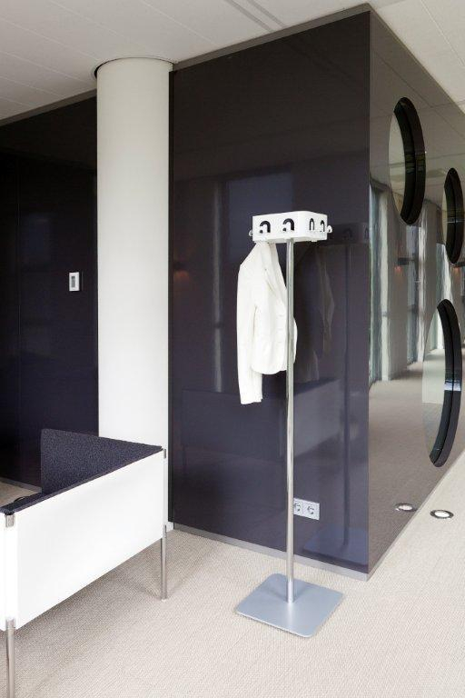 Freistehende Garderobe aus Metall mit weißem Blazer in modernem Büro- oder Empfangsbereich.