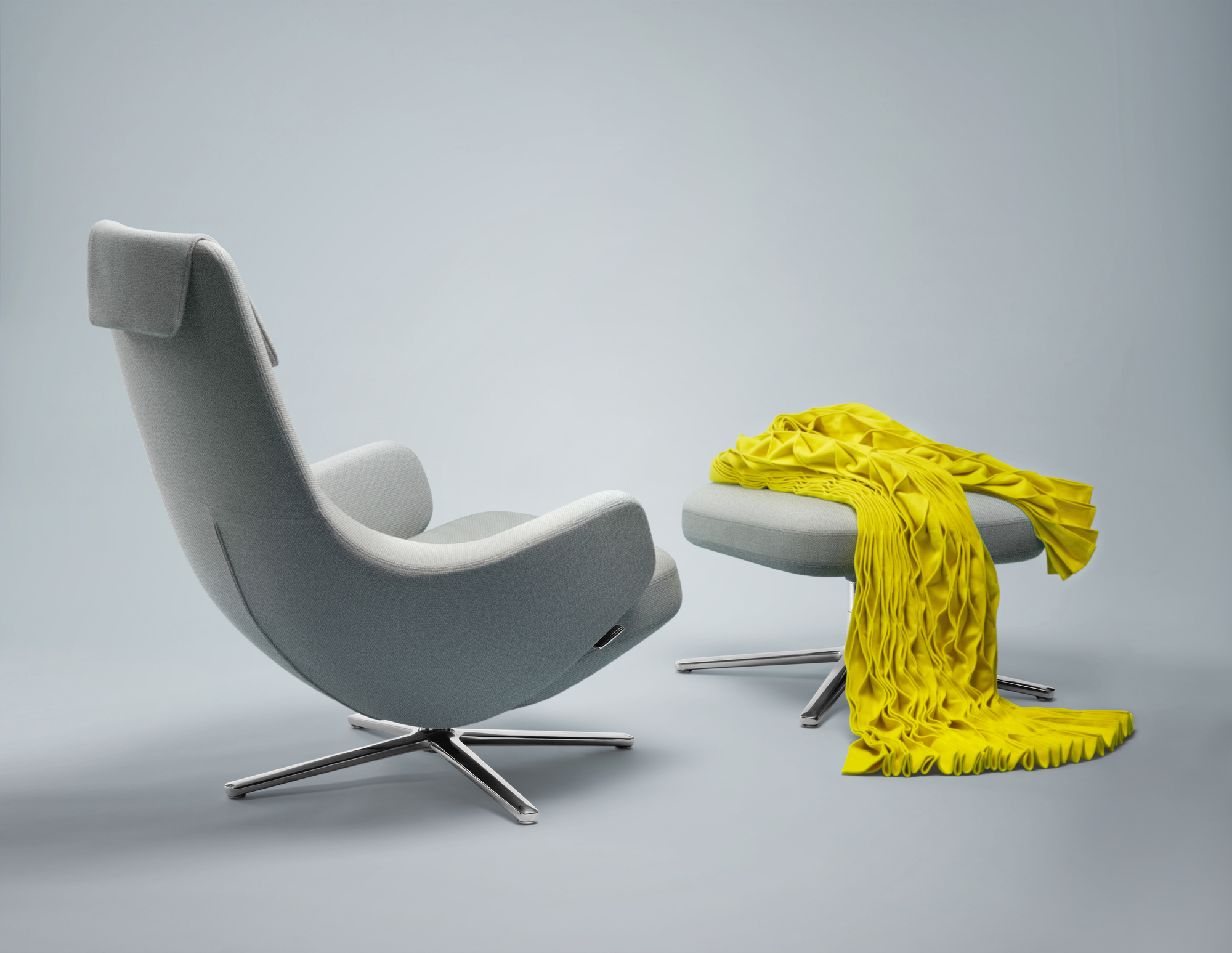 Grauer Repos Sessel mit Ottoman von Vitra und gelber Decke. Design Möbel für Wohnzimmer.