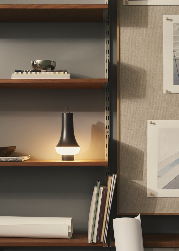 Tomoshi Akkuleuchte von Louis Poulsen in Dunkelbraun auf Holzregal, warmes Licht, modernes Design.