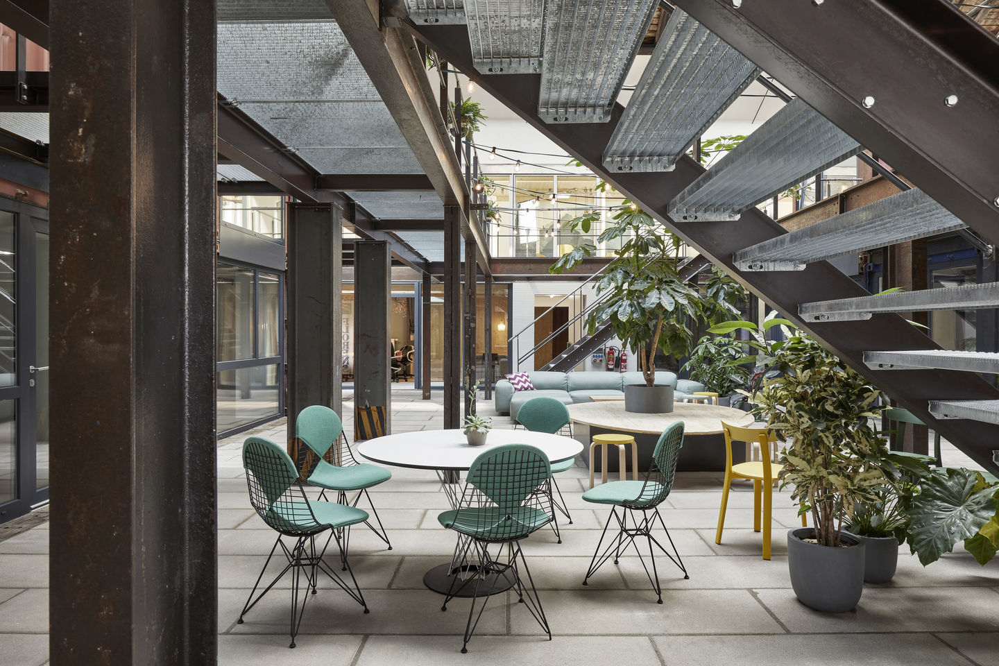 Vitra DKR Wire Chair Stühle mit grüner Polsterung um weißen Tisch in modernem Büro.