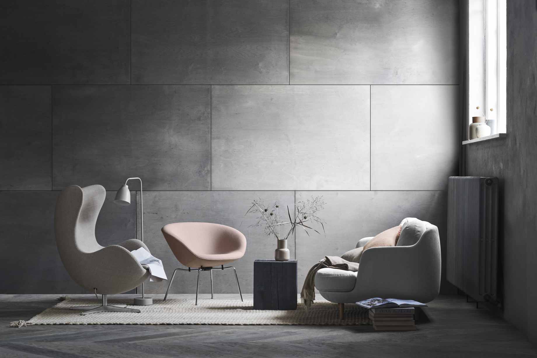 Helles Wohnzimmer mit Fritz Hansen Sesseln und einem Lune Sofa in Weiß vor grauer Wand.