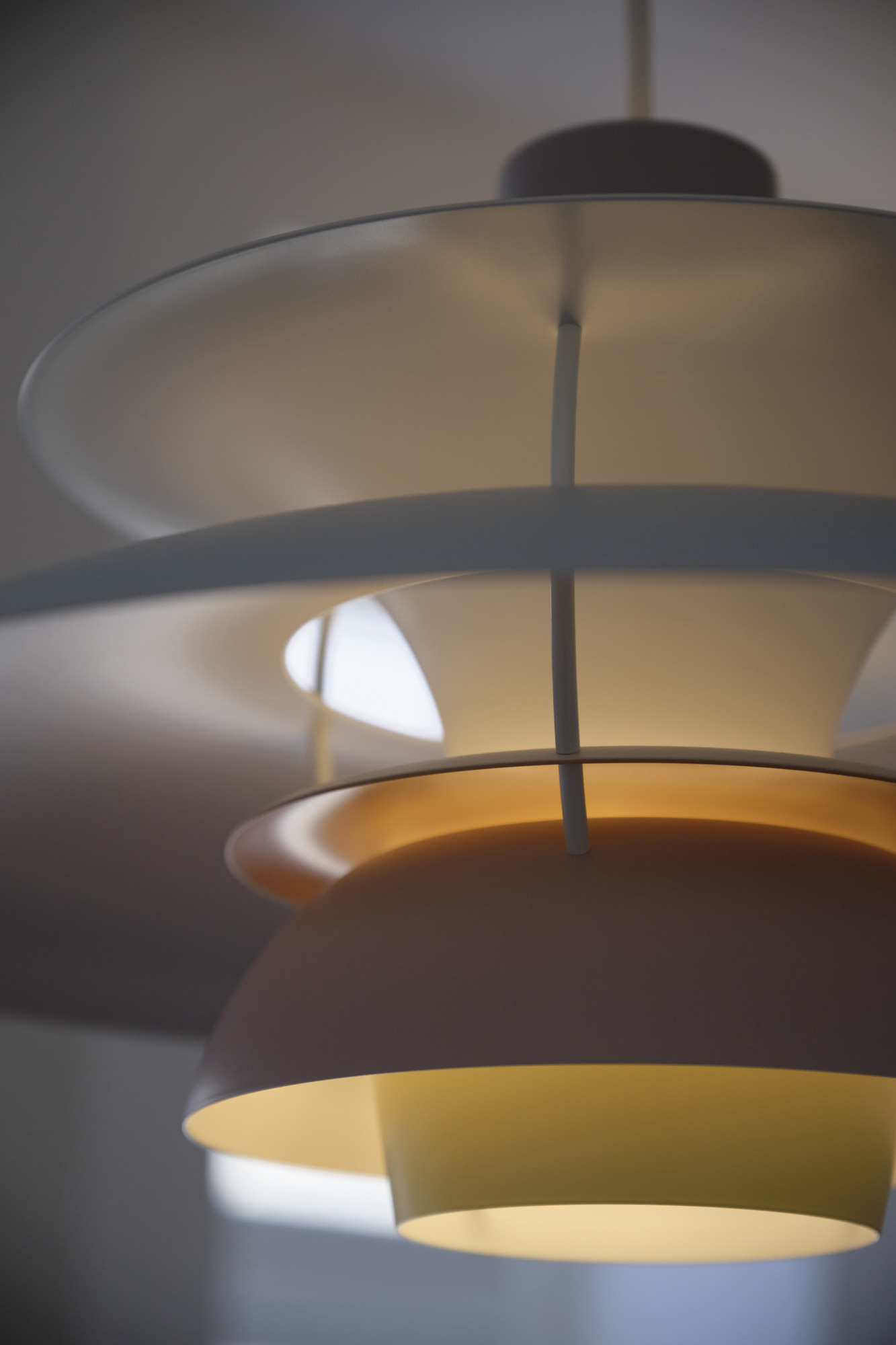 Detailaufnahme der Louis Poulsen PH 5 Pendelleuchte in Weiß und Gelb, modernes Design für Wohnraumbeleuchtung.