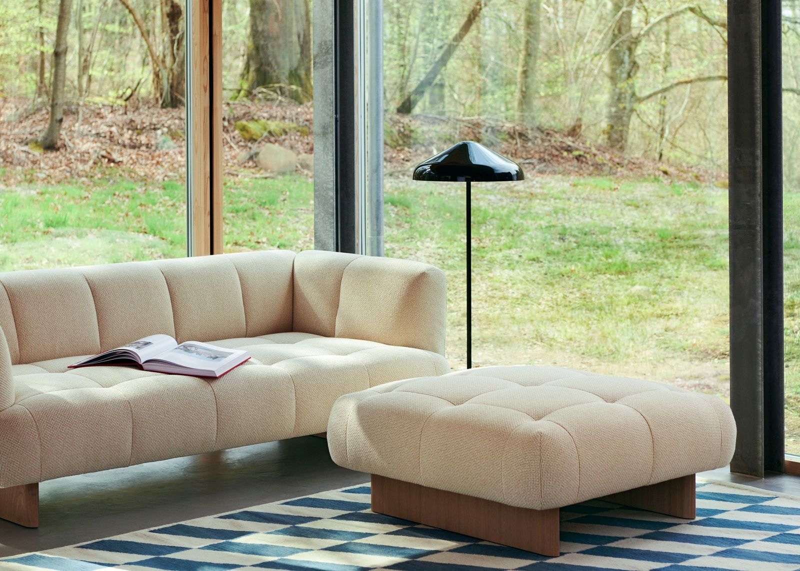 Wohnzimmer-Szene mit beigem Sofa, Hocker und Hay Shift Kelim Rug Teppich mit blau-weißem Schachbrettmuster.