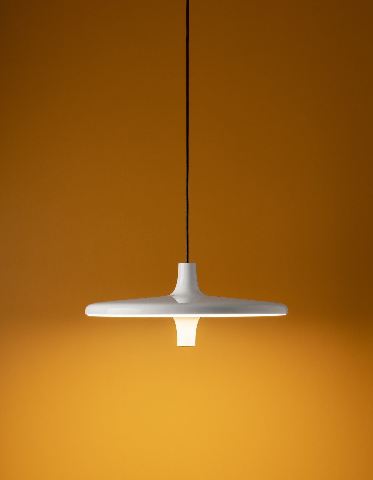 Avro Hängeleuchte von Martinelli Luce, moderne Pendelleuchte in Weiß mit warmem Licht vor ockerfarbenem Hintergrund.