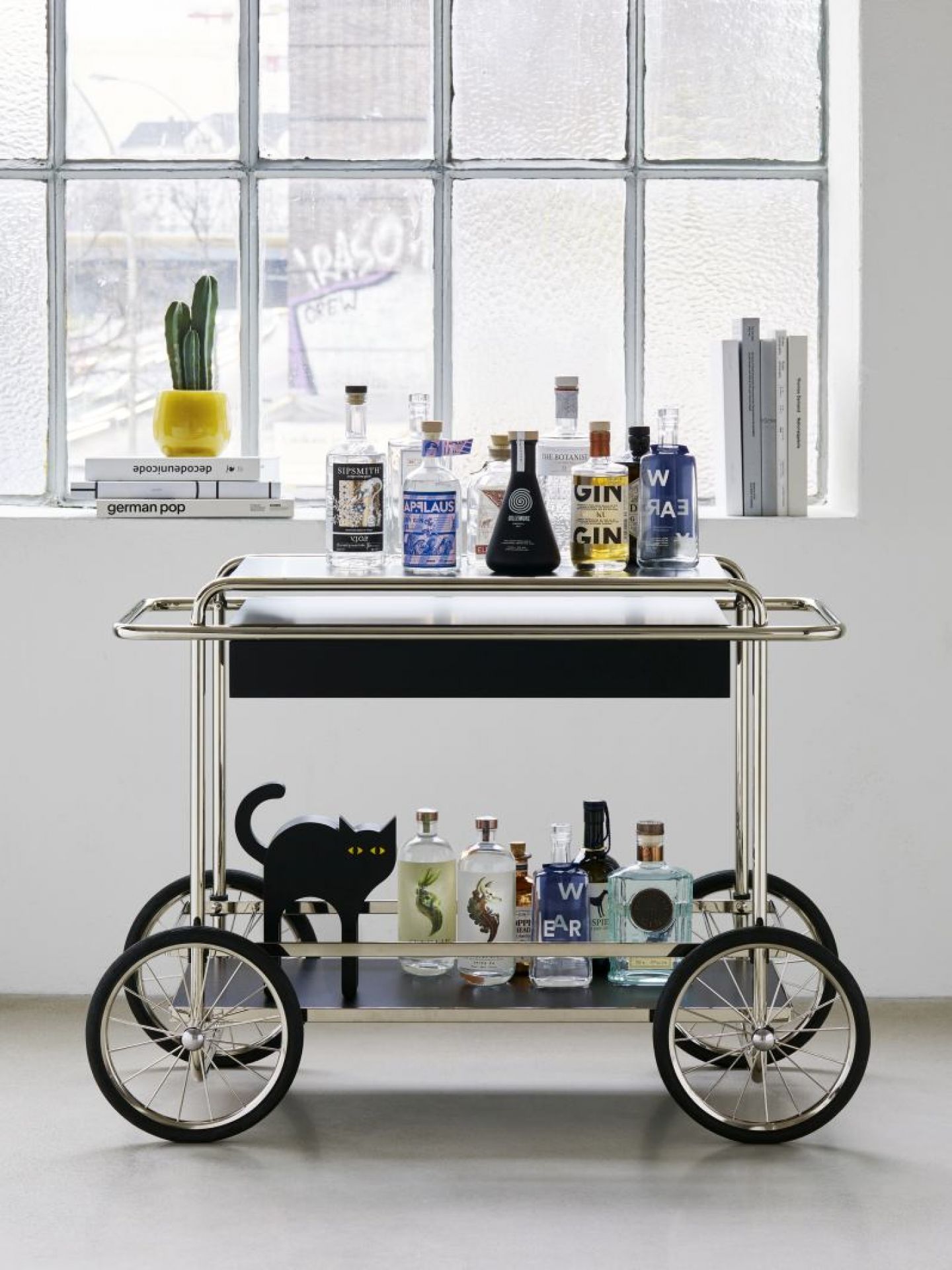 Silberfarbener Barwagen mit Gin-Flaschen und schwarzer Katze, ideal für stilvolle Partys und Cocktailabende.