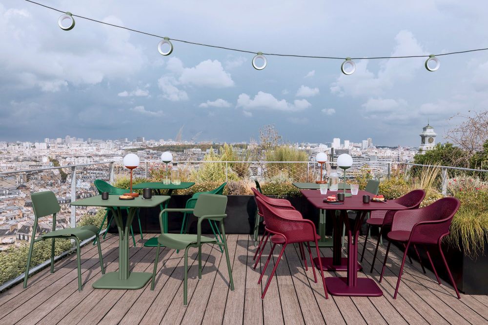 Grüne und rote Studie Chair Stühle von Fermob auf einer Dachterrasse mit Stadtblick.