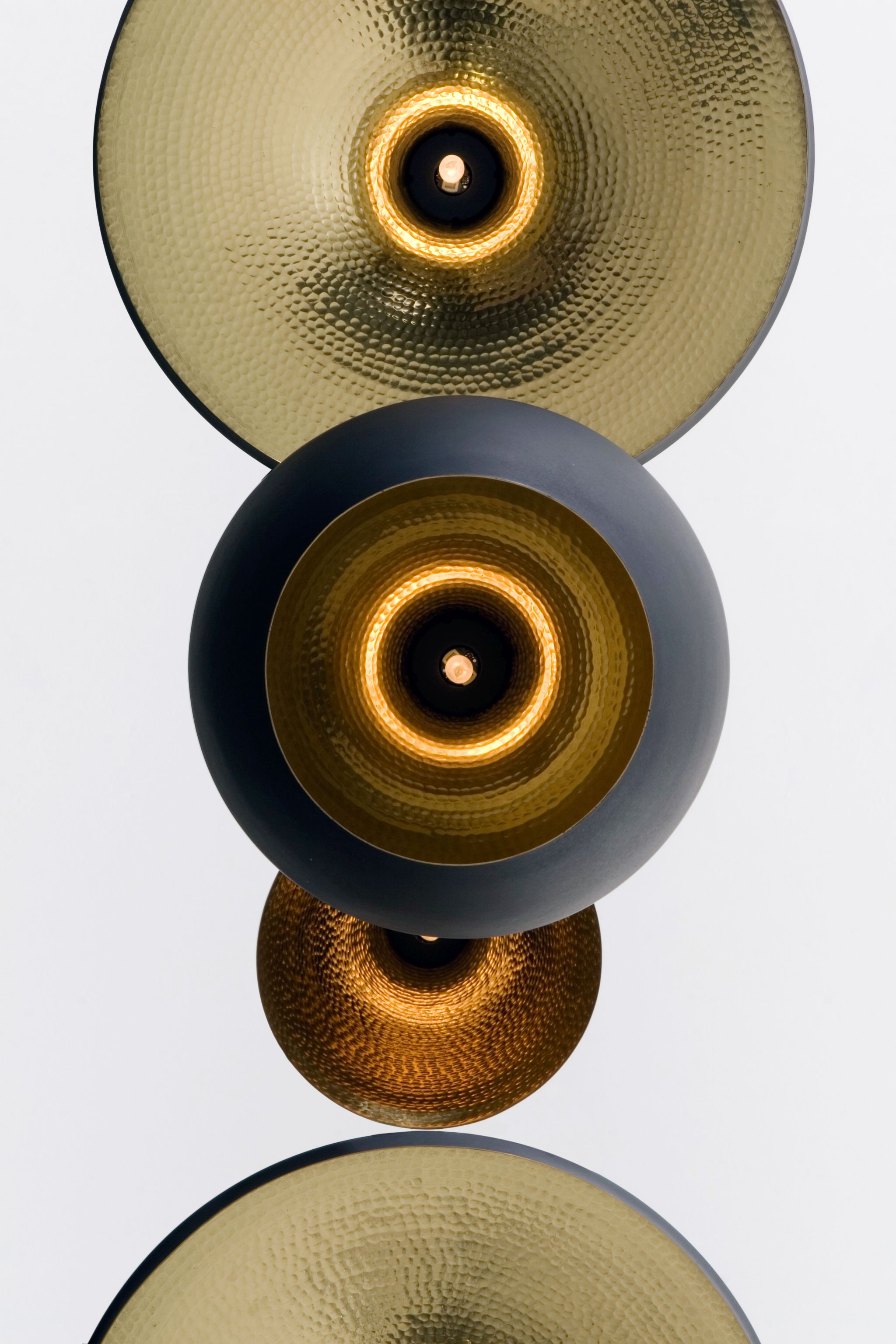 Nahaufnahme der Tom Dixon Beat Wandleuchte mit gehämmertem Messingschirm und warmem Lichtschein.