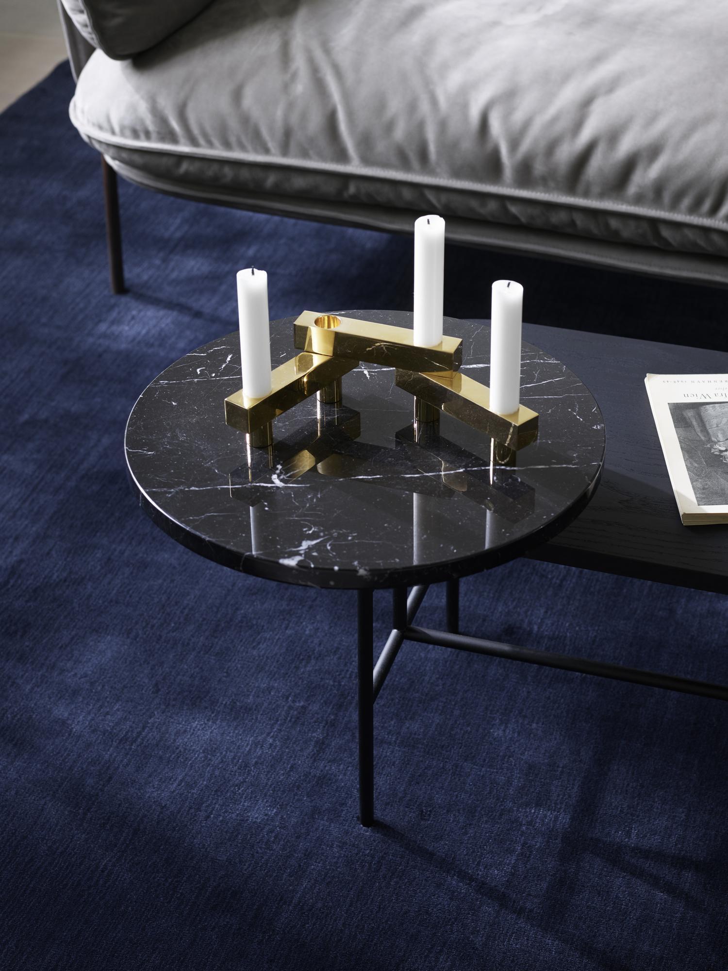 AndTradition Palette Table JH7 Couchtisch mit Marmorplatte, Kerzen und goldenem Kerzenständer auf blauem Teppich.