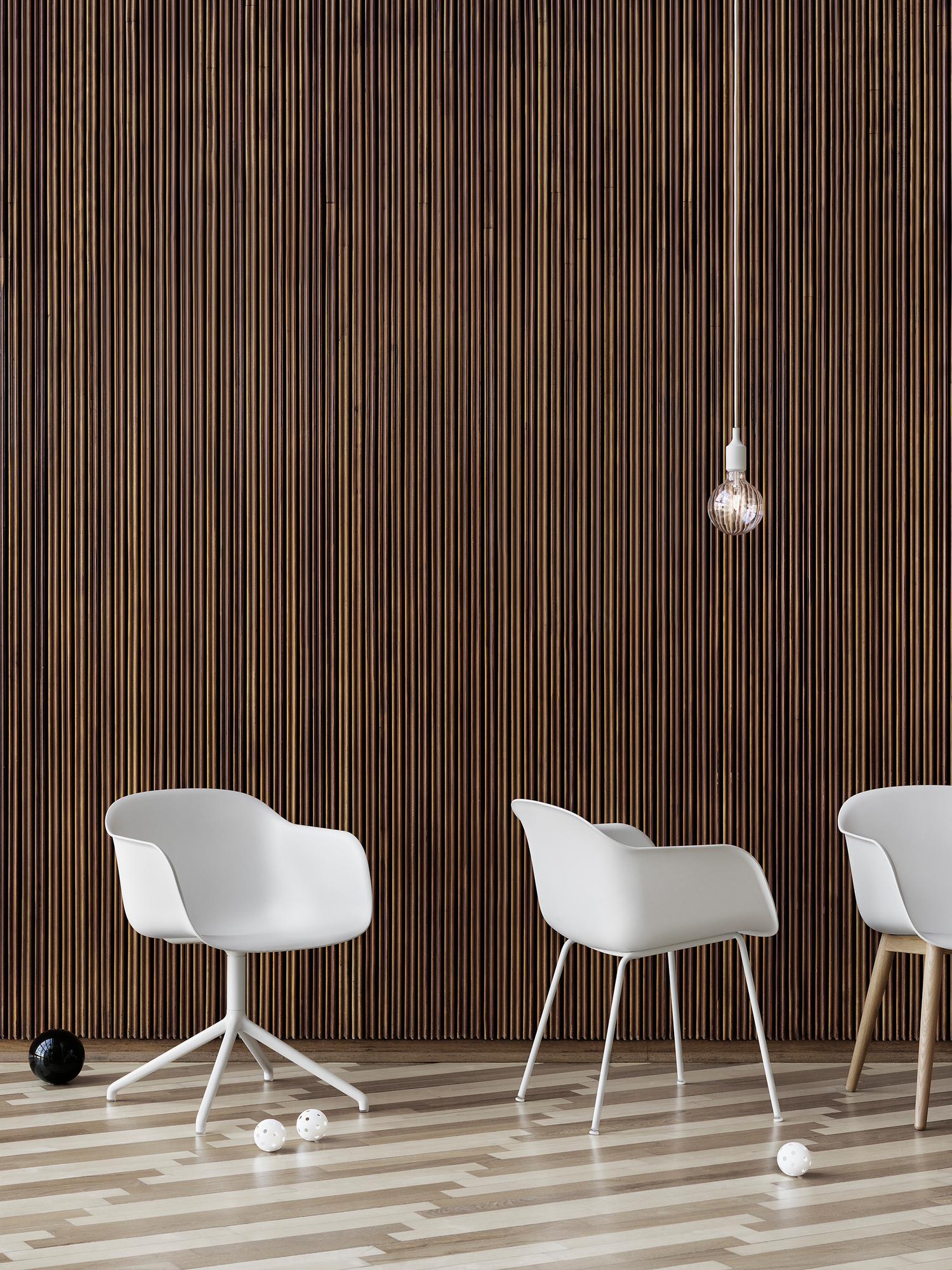 Weißer Fiber Armchair von Muuto mit Tube Base Gestell vor einer Holzpaneelwand.