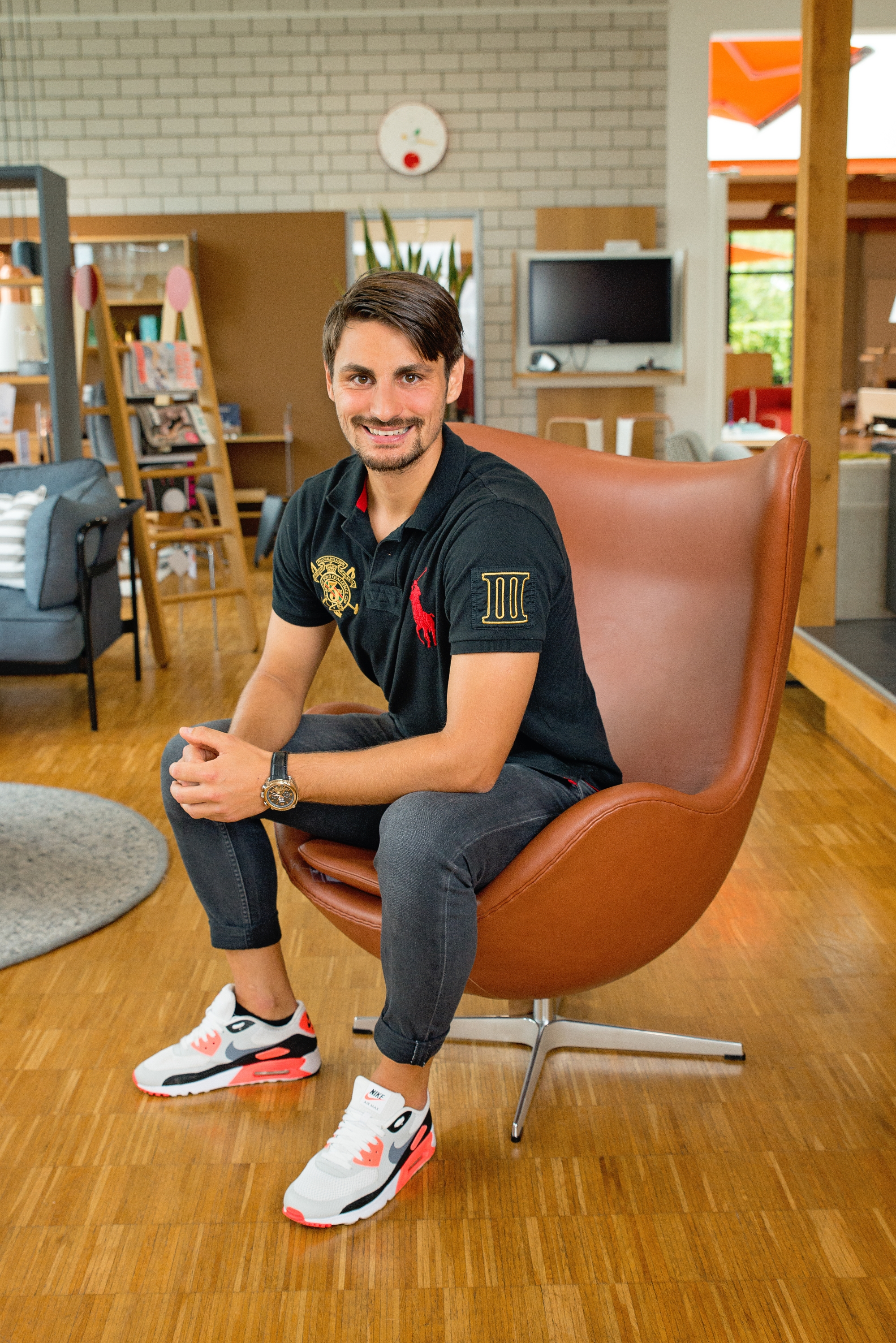 Mann sitzt entspannt im braunen "Das Ei" / Egg Chair Sessel von Fritz Hansen.