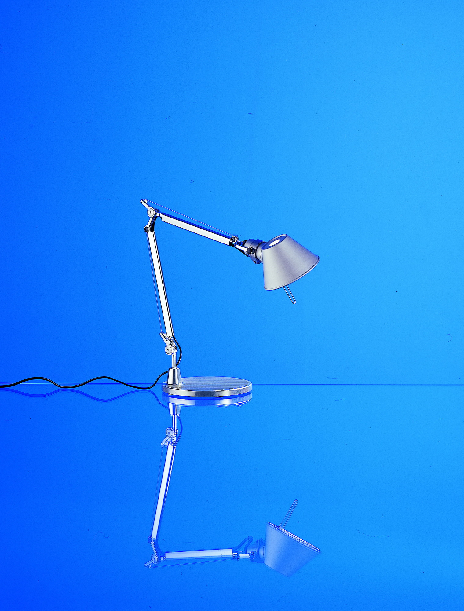 Silberne Artemide Tolomeo Micro Tischleuchte mit Fuß auf blauem Hintergrund, modernes Design.