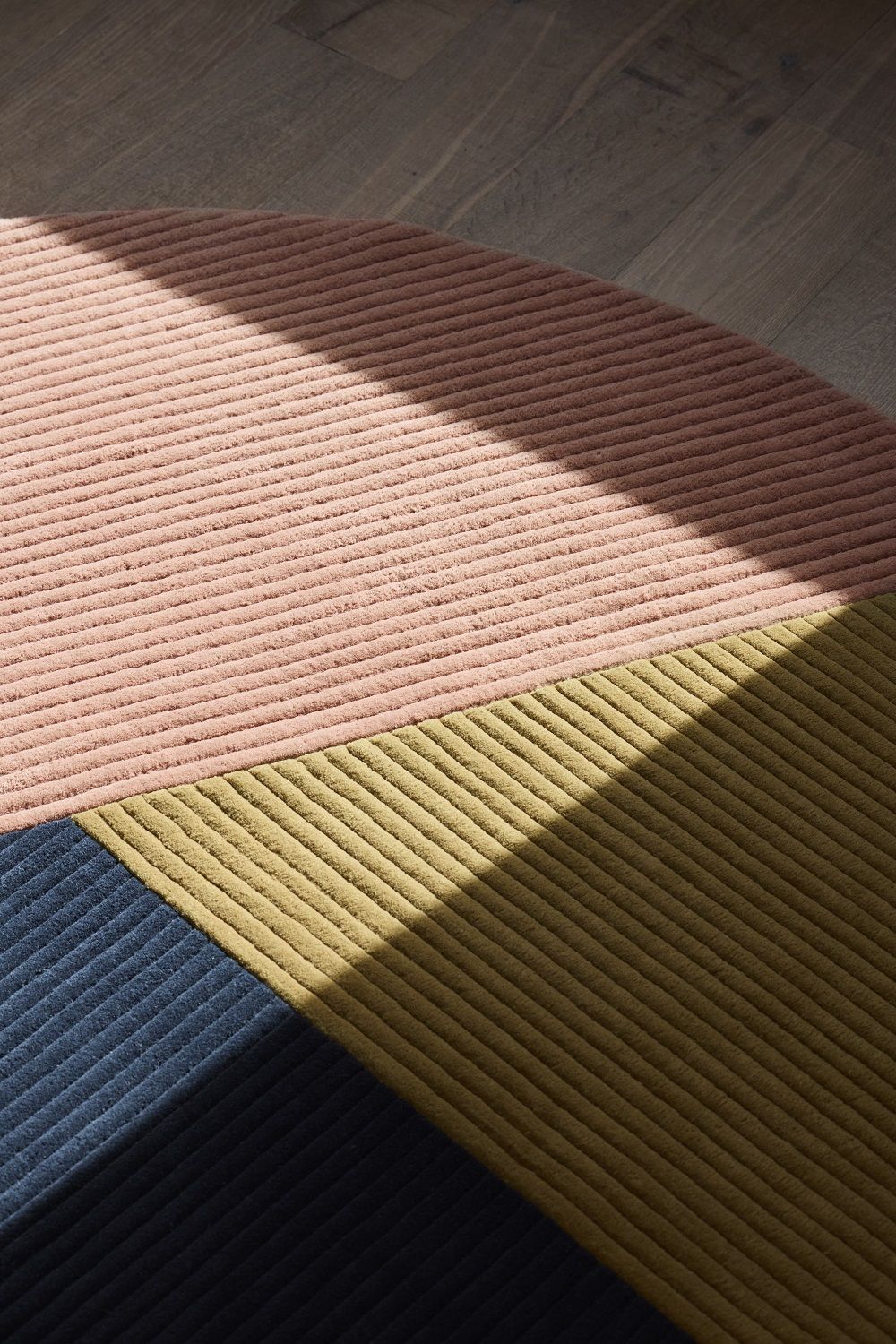 Detailaufnahme des Row Rug Circular Teppichs Northern mit rosa, olivgrünen und marineblauen Farbsegmenten.