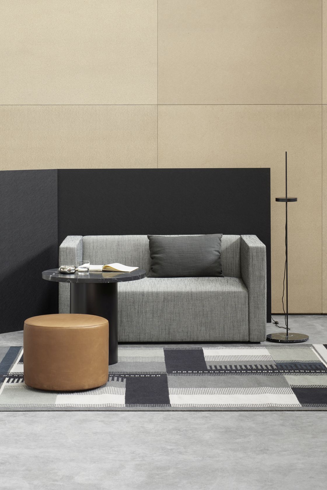 Enoki CT09 Beistelltisch e15 aus Marmor neben Sofa und Hocker im modernen Wohnzimmer.